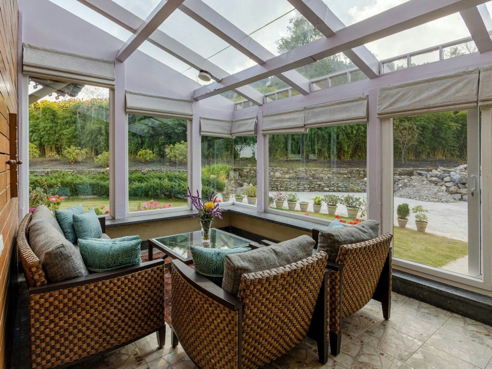 Wicker armchairs in a sunlit conservatory overlooking a garden.