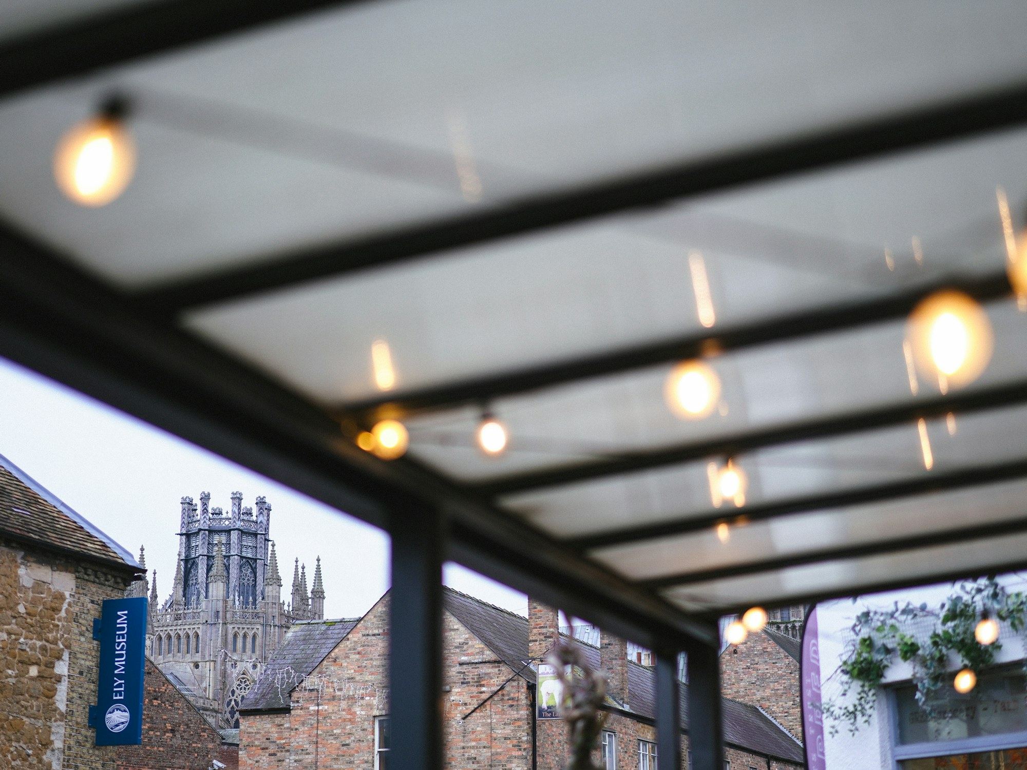Glass canopy with hanging lights and a distant cathedral tower