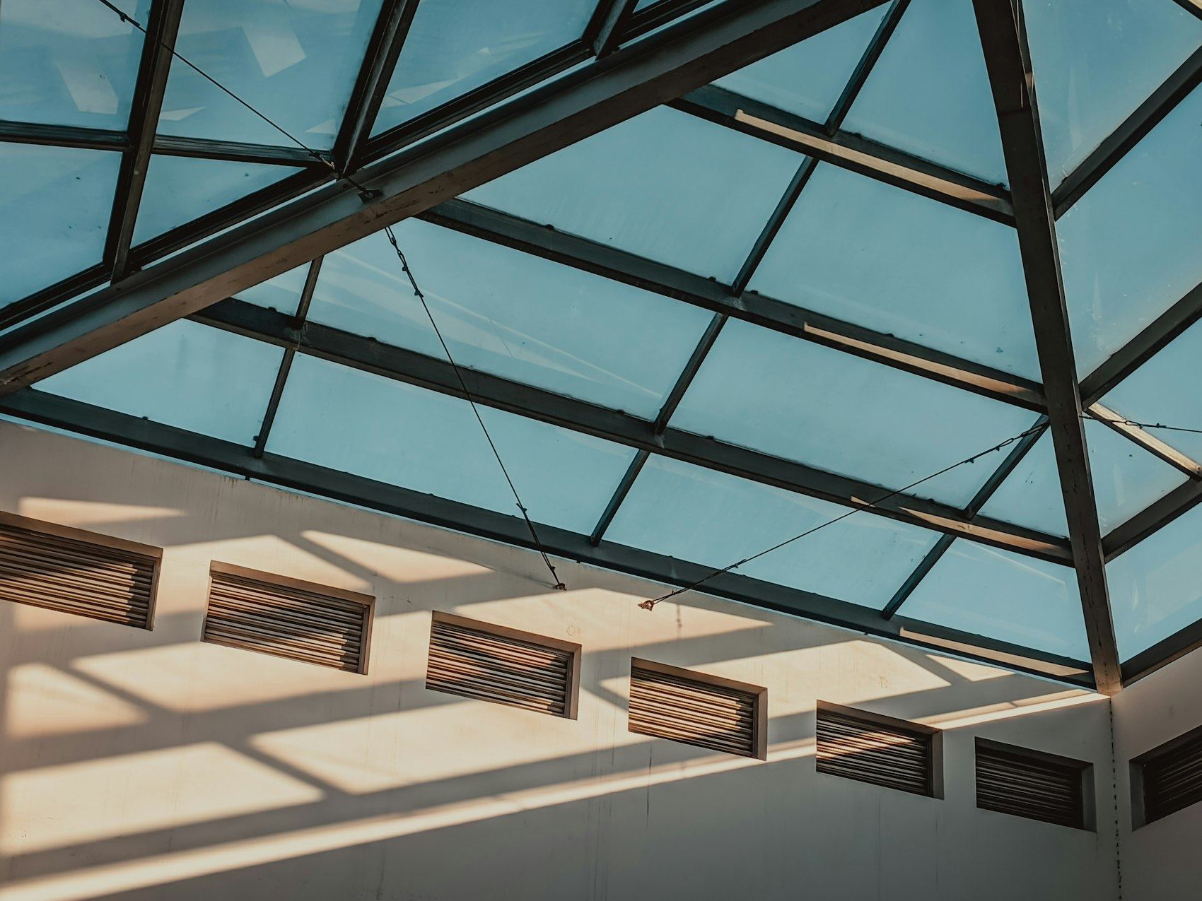 Interior view of a glass conservatory roof with sunlight streaming through.