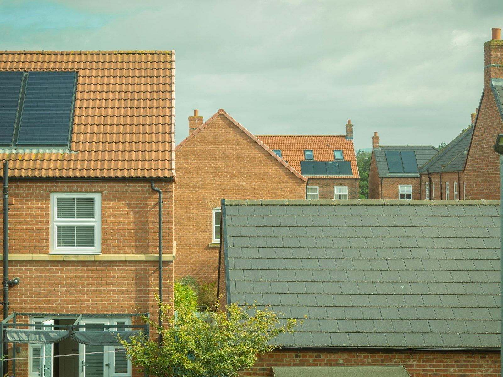 Rooftops of modern brick houses with solar panels under a cloudy sky