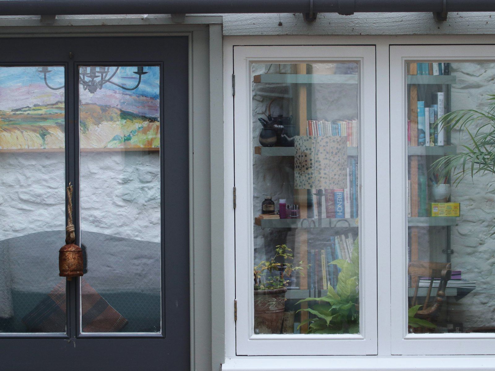 Close-up of a dark door and white window with books inside