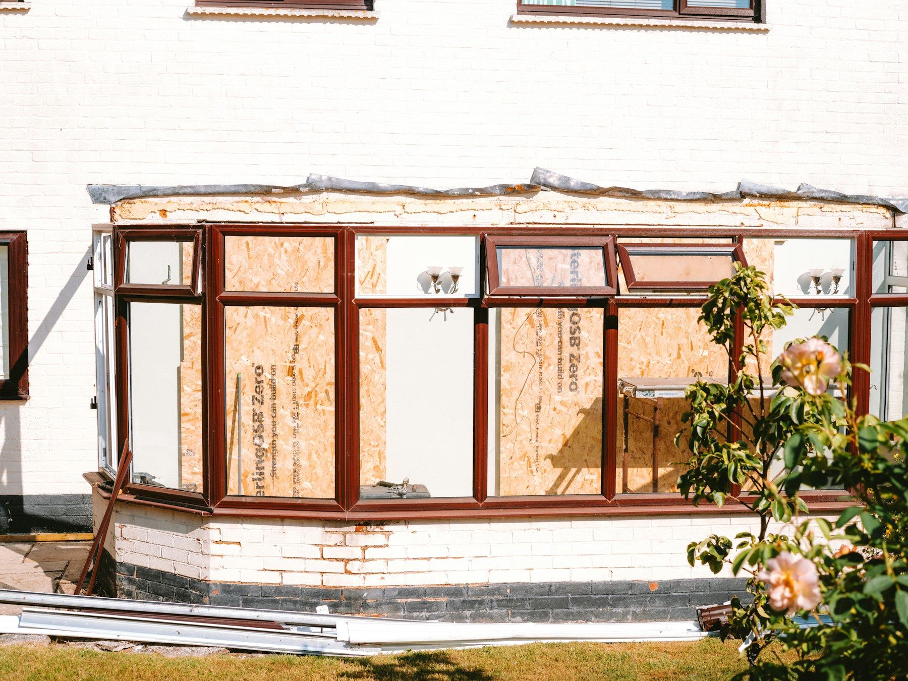 Conservatory under construction with boarded-up window panels.